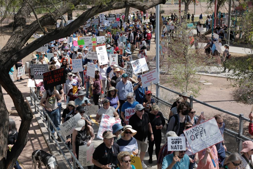 A crowd of peaceful protesters marches through a park in Tempe